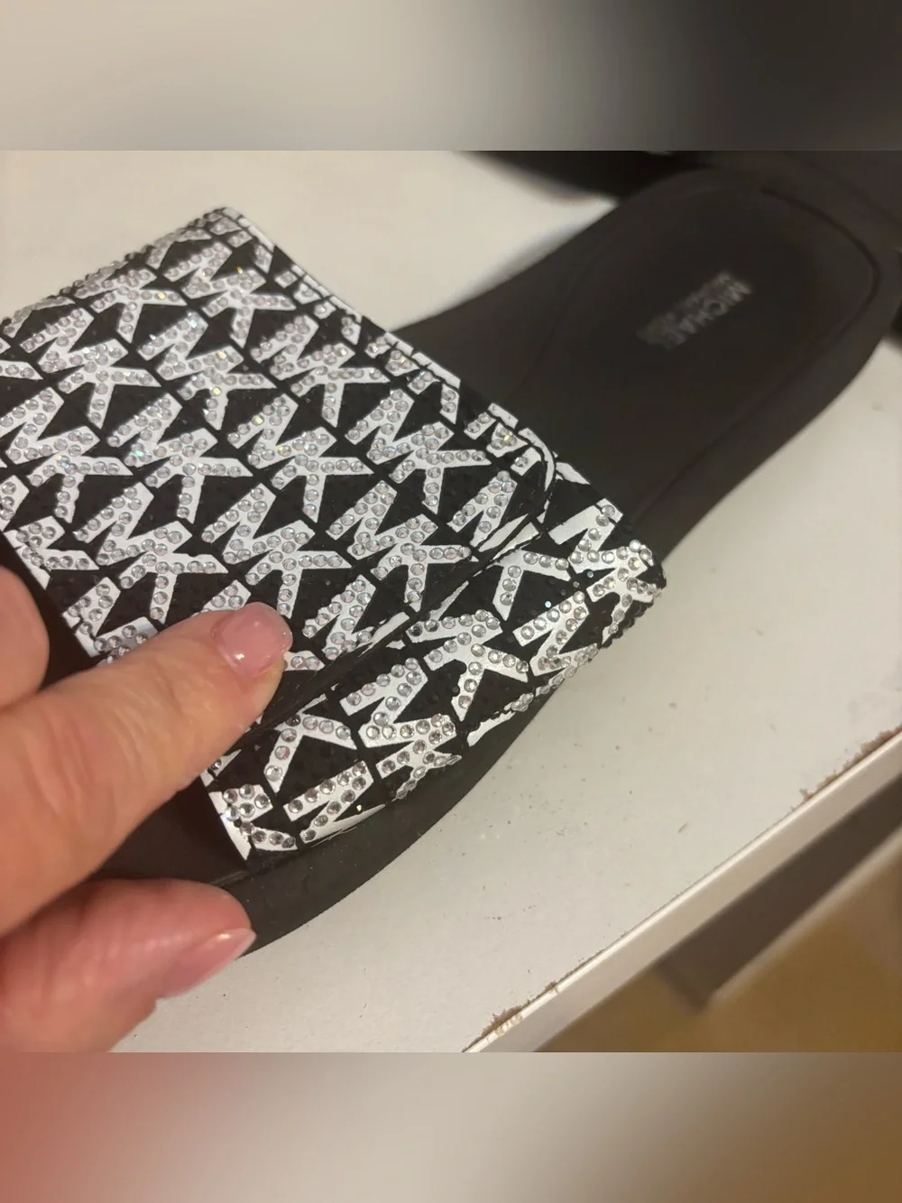 Michael Kors black & white slides featuring a signature logo print on the strap.